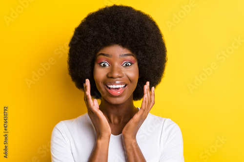 Photo of amazed nice dark skin young woman raise hands impressed news isolated on yellow color background