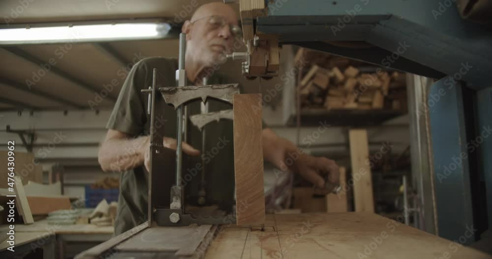 old Carpenter pulls a wooden block on a saw old Carpenter pulls a wooden block on a saw