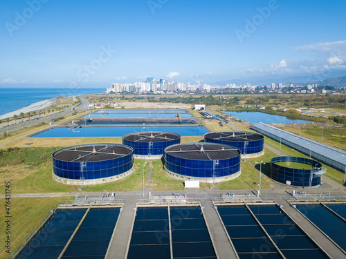 Drone view of sewage treatment plants, filtration of dirty or waste water near the sea. Stage of primary deposition, wastewater passes through large round tanks with mechanically driven scrapers.