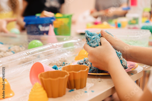 kinetic sand. children's hands play with multi-colored polymer sand.
