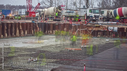 View of a busy building construction site in timelapse during autumn. Workers working at a construction site in Riga, Latvia (2018)with many concrete mixer trucks lined up delievering cement. photo