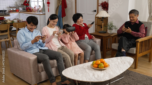 asian family members addictive to electronics are playing with smartphones  vr glasses and watching tv in the living room at home during Chinese new year