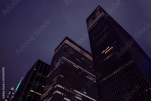 Modern city building office at night. Low angle view of skyscrapers. Looking up perspective. Bottom view of modern skyscrapers in a business district. Cityscape at night.