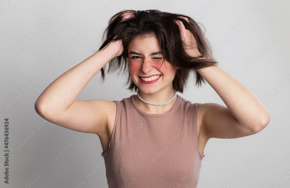 It's time to go to the beauty salon. Casual woman face expressions she does not go to spa, hair salon or beauty salon for long time. over gray background copy space.
