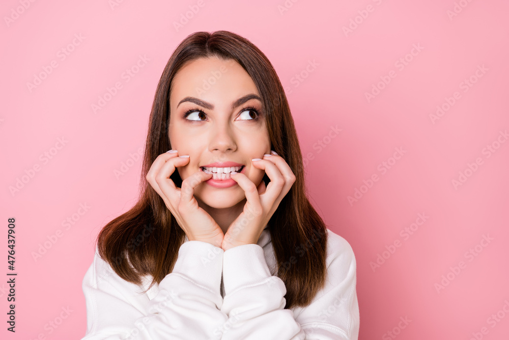 Photo of young girl happy positive smile bite fingers lips look empty space isolated over pink color background Photo of young girl happy positive smile bite fingers lips look empty space isolated over pink color background