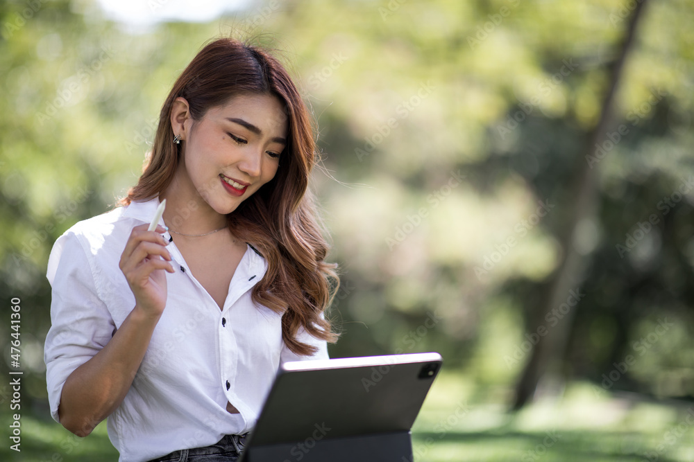 Joyful casual Asian student girl with laptop outdoors. Smiling woman sitting on the grass with a computer, surfing the net or preparing for exams. Technology, education and remote working concept Joyful casual Asian student girl with laptop outdoors. Smiling woman sitting on the grass with a computer, surfing the net or preparing for exams. Technology, education and remote working concept