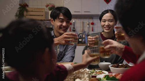 selective focus of happy young asian couple drinking toast with tea to their family at chinese chinese lunar new year reunion dinner at home. chinese text translation: fortune