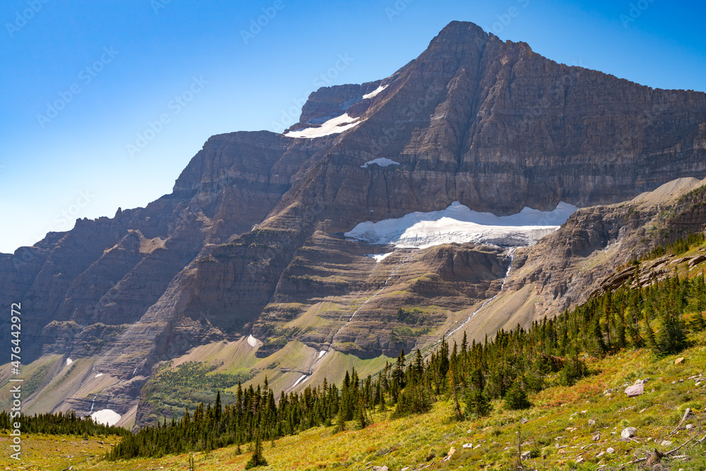 Fototapeta premium Matahpi Peak and valley below viewed from Siyeh Pass hiking trail, Glacier National Park, Montana. Sunny summer day high in American Rockies. Mountain range and valley bellow on a sunny day.