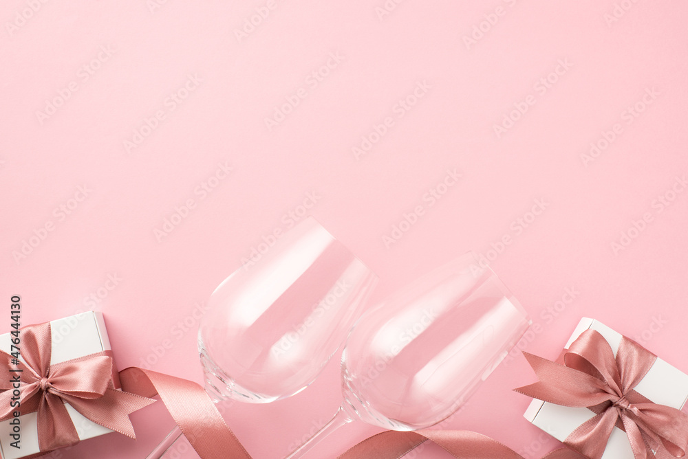 Top view photo of st valentine's day decorations two wineglasses pink satin ribbon and white gift boxes with bows on isolated pastel pink background with copyspace Top view photo of st valentine's day decorations two wineglasses pink satin ribbon and white gift boxes with bows on isolated pastel pink background with copyspace