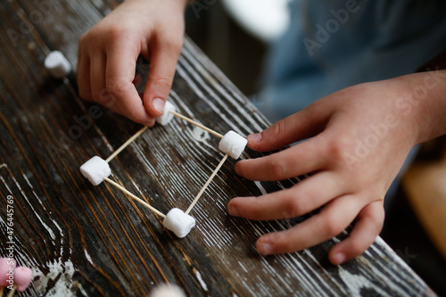 Children play with marshmallows and toothpicks, edible designer in the kitchen. Educational classes and games with children. Child development at home