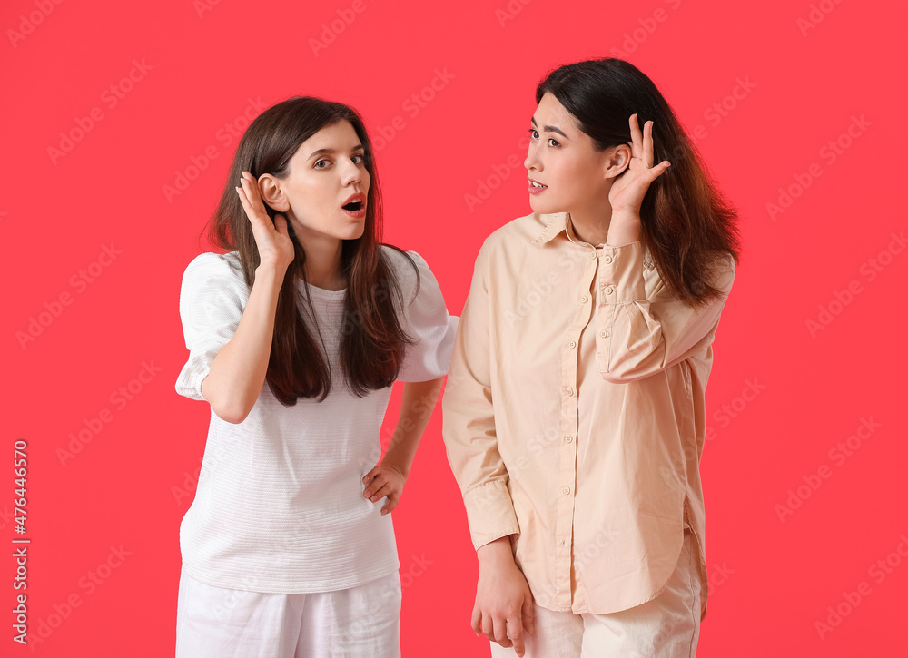 Young gossiping women on color background Young gossiping women on color background