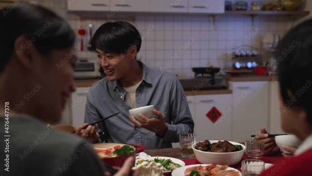 selective focus smiling asian father talking to family while enjoying tasty food at dinner table. people chatting happily during reunion meal on chinese lunar new year's eve at home selective focus smiling asian father talking to family while enjoying tasty food at dinner table. people chatting happily during reunion meal on chinese lunar new year's eve at home