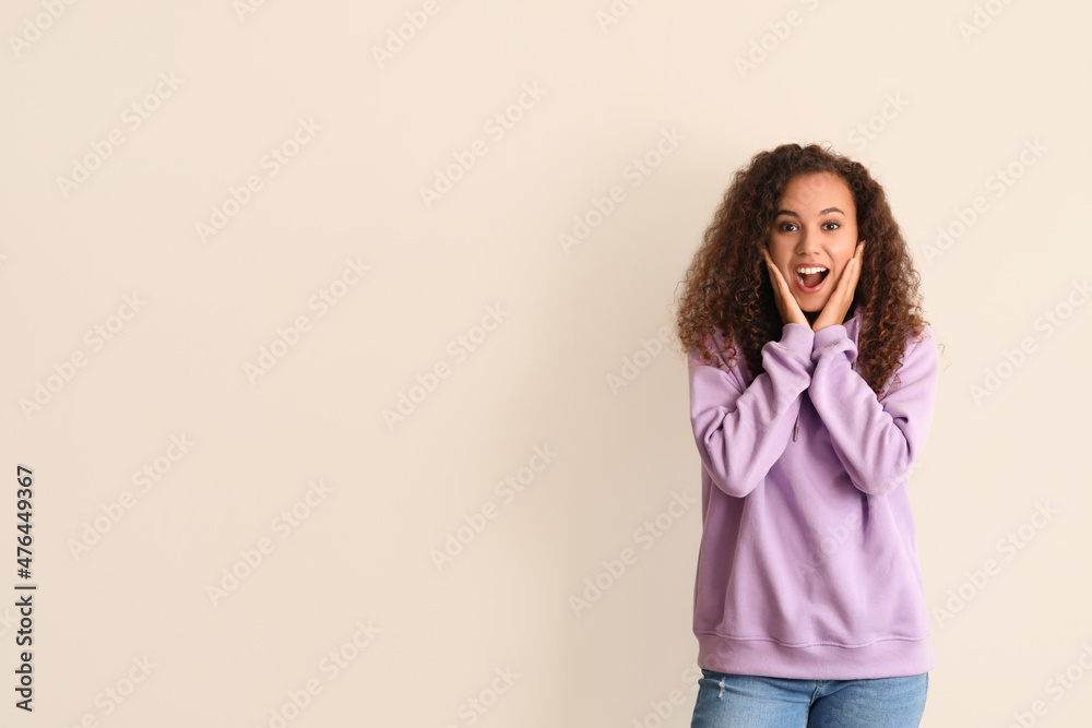 Surprised young African-American woman in stylish hoodie on light background Surprised young African-American woman in stylish hoodie on light background