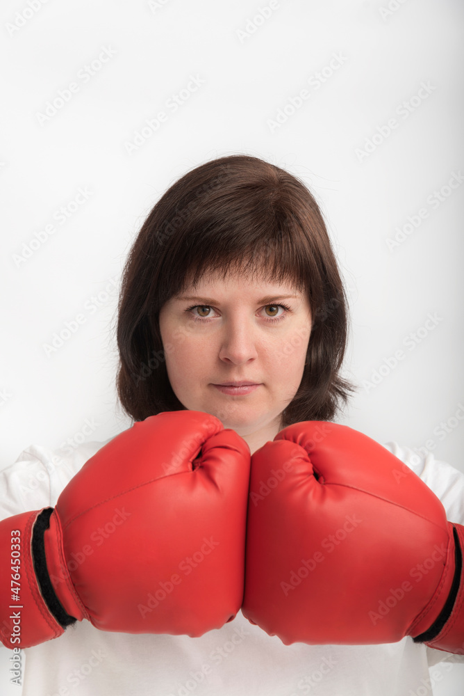 Portrait of young confident woman in boxing gloves on white background. Concept of feminism and the struggle for womens rights. Portrait of young confident woman in boxing gloves on white background. Concept of feminism and the struggle for womens rights.