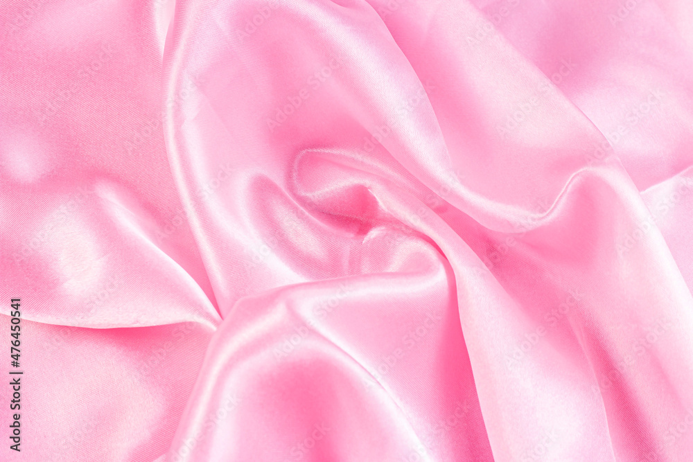 Obraz premium Light pastel pink color silk wavy textile pattern as a smooth textured background. Rose colored soft satin fabric drapery.
