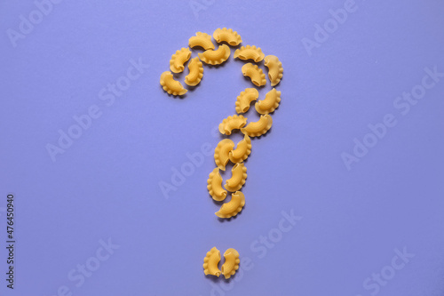 Question mark made of dry pasta on purple background