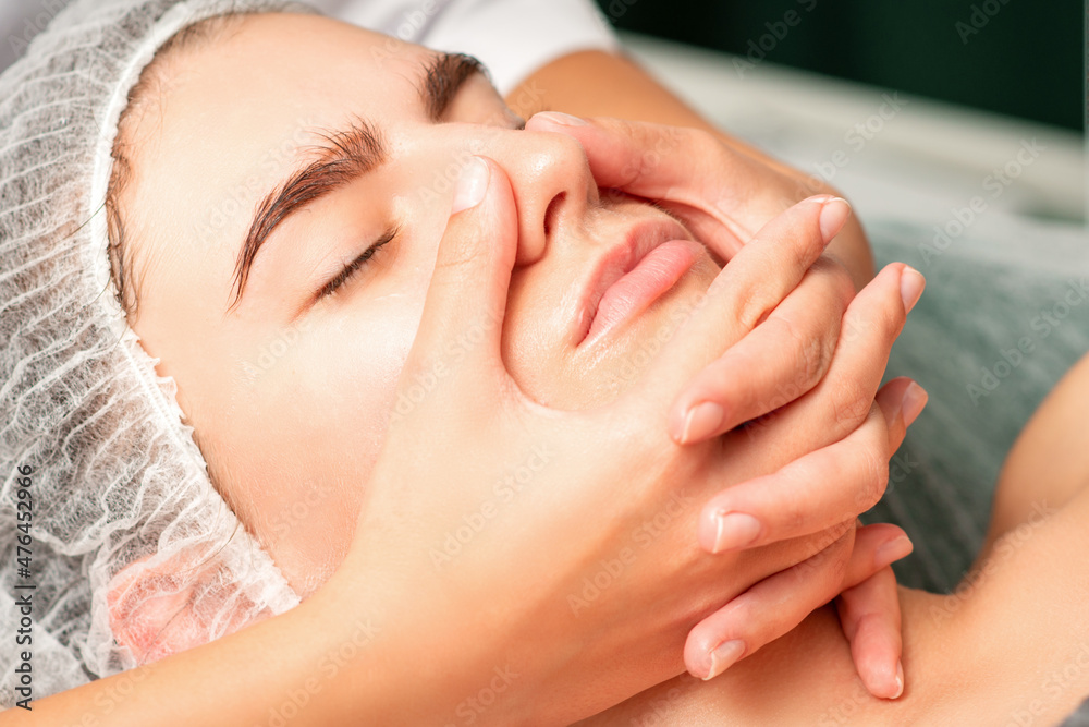 A young caucasian woman getting facial massage in a spa A young caucasian woman getting facial massage in a spa
