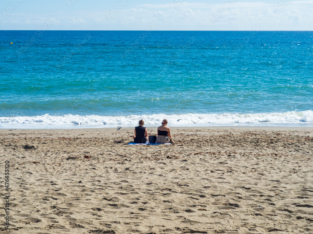 Dos chicas jóvenes sentadas en la orilla de la playa de Fuengirola Dos chicas jóvenes sentadas en la orilla de la playa de Fuengirola