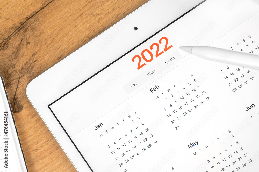 2022 calendar close-up, tablet computer screen. Business wooden table desktop background. Concept photo of planning appointment and meeting 2022 calendar close-up, tablet computer screen. Business wooden table desktop background. Concept photo of planning appointment and meeting