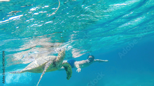 Quadro su tela A man in a diving mask and fins diving along a turtle, next to the shore of Gili Air, Lombok Indonesia
