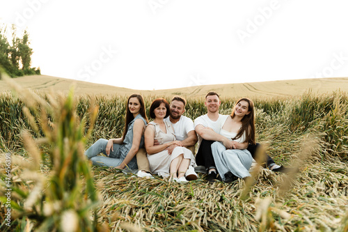 a family of farmers sits in a wheat field at sunset and rejoices, organic harvest, eco wheat is grown by a family, a family of five are resting in a field