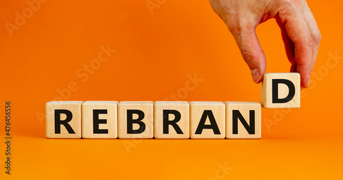 Rebrand and brand symbol. The concept word Rebrand on wooden cubes. Beautiful orange table, orange background, copy space. Businessman hand. Business rebrand and brand concept. photo