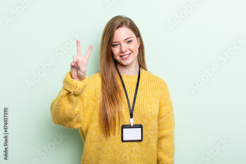 redhair smiling and looking friendly, showing number two. accreditation card concept photo