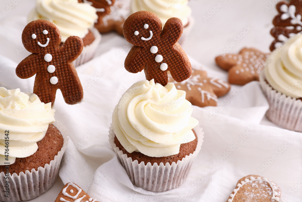 Tasty Christmas cupcakes with gingerbread cookies on light background Tasty Christmas cupcakes with gingerbread cookies on light background