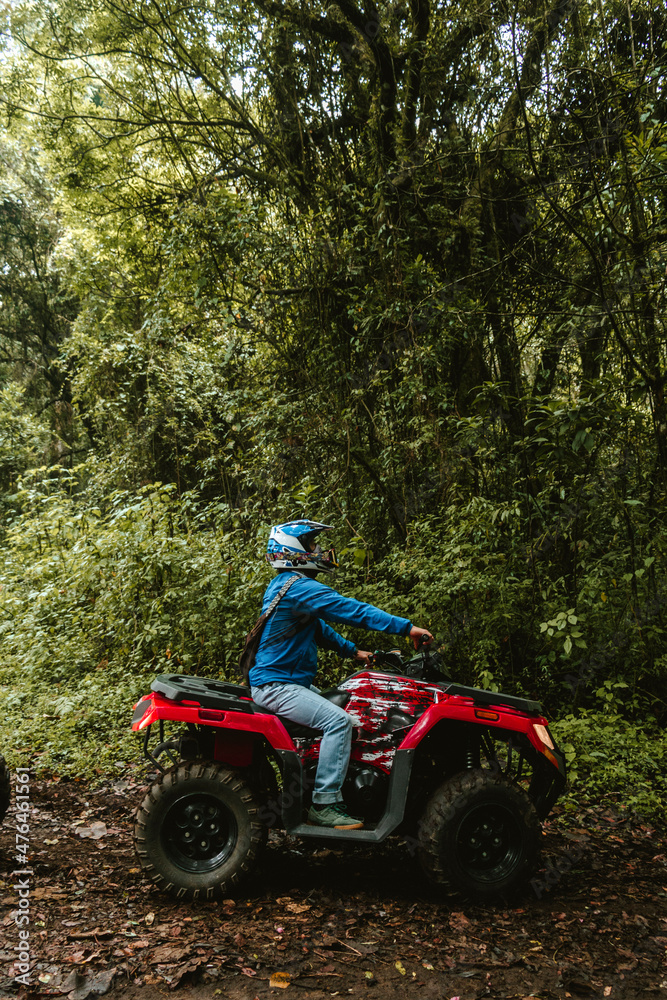 Hombre latino en cuatri moto en medio del bosque