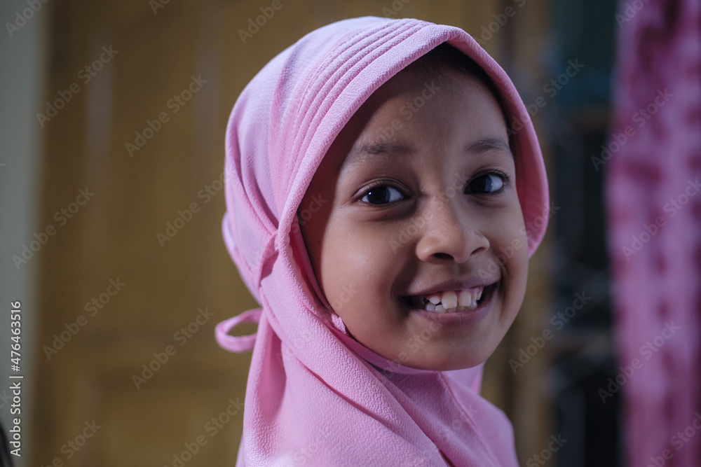 Cute Asian Muslim girl wearing a hijab or pink Islamic dress.