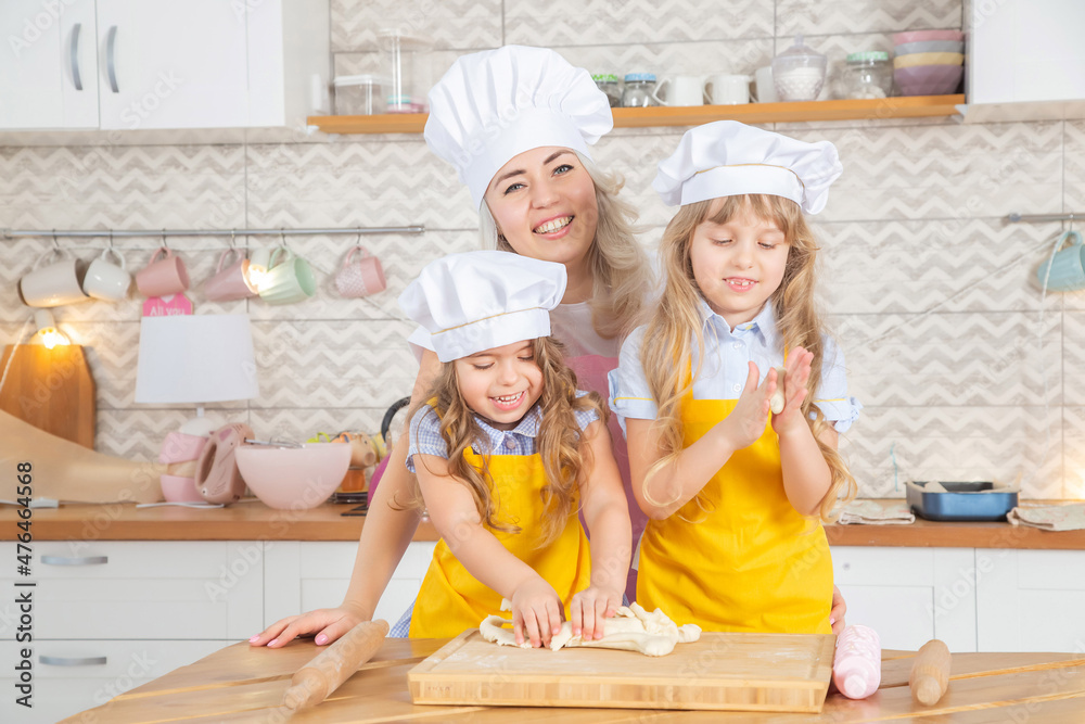 30 years old caucasian mother helping her cute litte daughters rolling dough. 30 years old caucasian mother helping her cute litte daughters rolling dough.