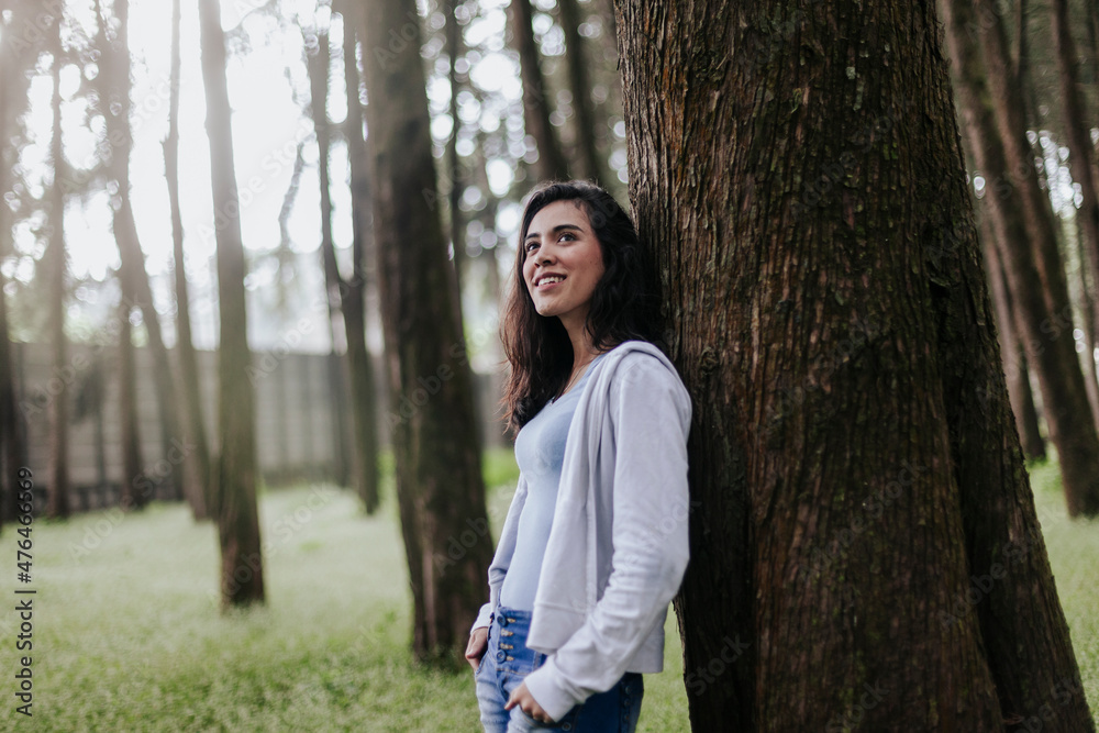 Mujer joven con pelo largo sonriendo en bosque