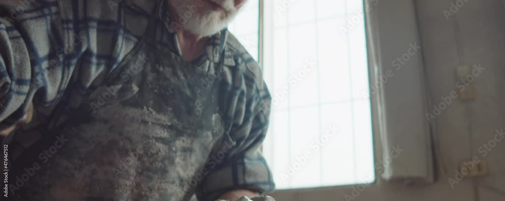 Close up shot of senior potter coning up clay on wheel while making ceramics in workshop