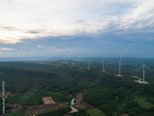 Aerial View of a wind turbine on top of mountains, blue sky as background. - Sustainable development, environment friendly, renewable energy concept.