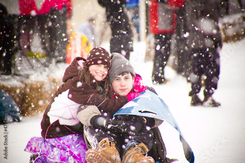 Siblings posing for a picture during a snowfall