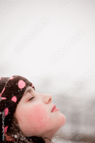 Child playing in a snowfall. Outdoors winter activities for kids. Cute child wearing a warm hat low over his eyes meditating