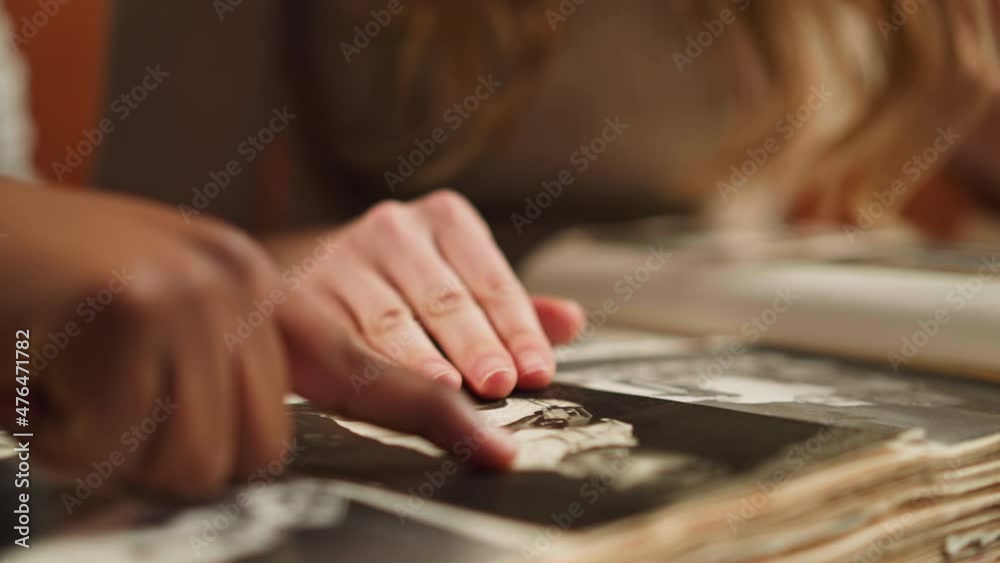 White woman with African-American husband touches baby picture of relative looking at old photo-book in living room closeup slow motion White woman with African-American husband touches baby picture of relative looking at old photo-book in living room closeup slow motion