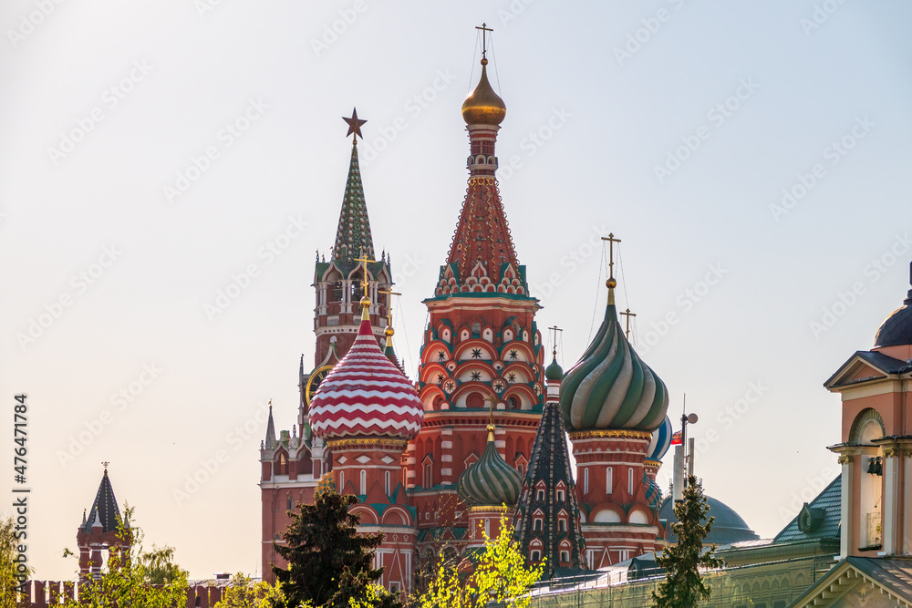 Multi-colored domes of St. Basil's Cathedral and the Spasskaya Tower of the Moscow Kremlin around the trees. Symbols of the Russian state. Multi-colored domes of St. Basil's Cathedral and the Spasskaya Tower of the Moscow Kremlin around the trees. Symbols of the Russian state.