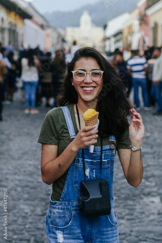 young girl with glasses and perfect teeth eating ice cream in tourist city