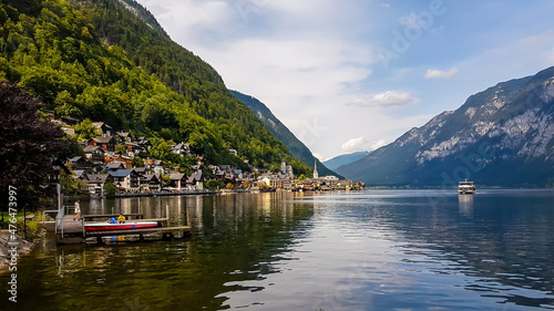 A small village located by the lake in Hallstatt, Austria. The calm surface of the lake reflects the village and the mountains. Alpine village. Idyllic landscape. Coexistence of human and nature.
