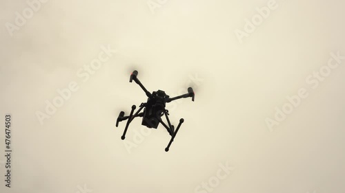 An unmanned helicopter with a video camera hovers in the sky. Modern military drone.