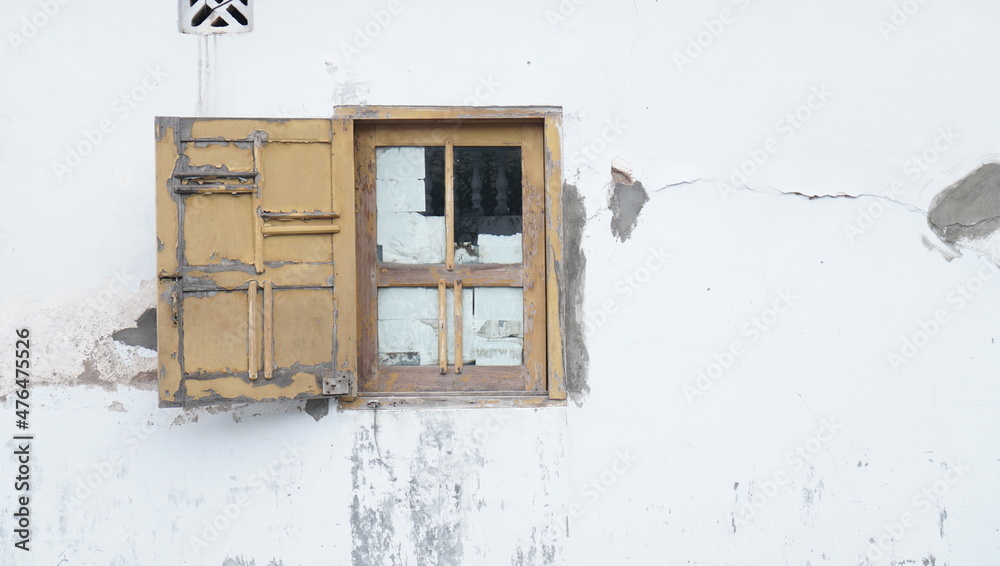 old window on a damaged wall building. a facade of an aged and abandoned building with a damaged wooden window. rough background suitable for copy space. old window on a damaged wall building. a facade of an aged and abandoned building with a damaged wooden window. rough background suitable for copy space.