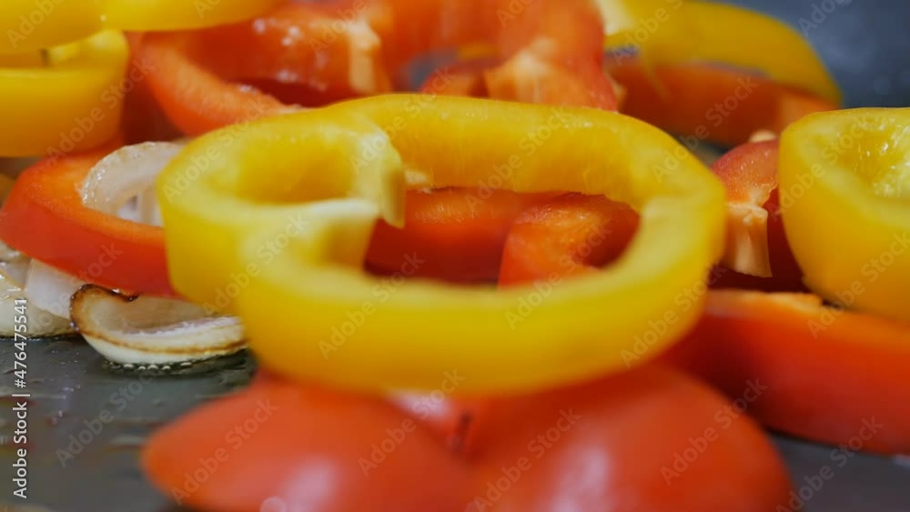 yellow and red bell peppers, sliced into rings, dip in a pan in fried onions, slow motion, dolly shot yellow and red bell peppers, sliced into rings, dip in a pan in fried onions, slow motion, dolly shot