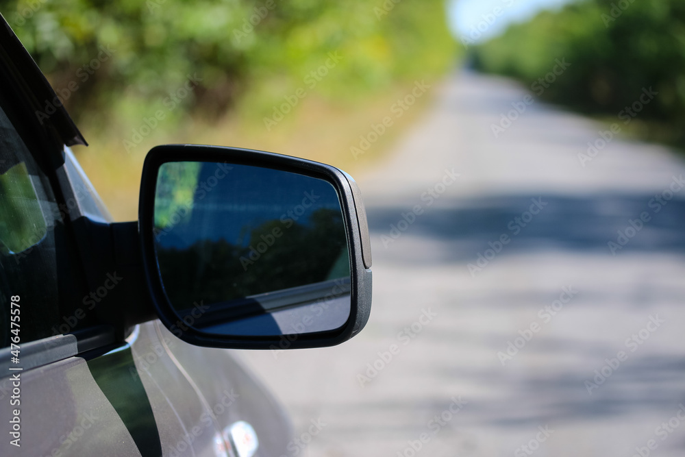 car side rearview mirror in the parking lot of a country highway
