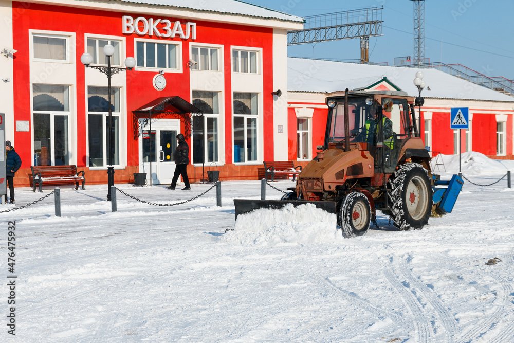 Samara, Chapaevsk, Russia-February.20.2018: Snow plow truck cleaning forecourt area streets Winter snow removal concept city landscape background horizontal - obrazy, fototapety, plakaty 