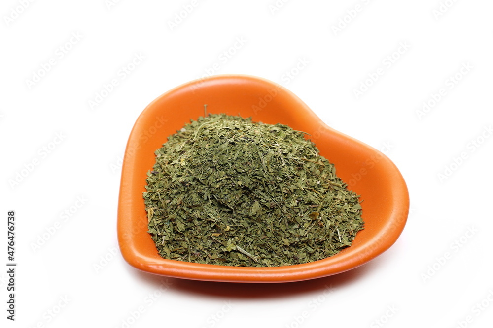 Chopped dry parsley leaves, pile in shape heart, porcelain bowl isolated on white Chopped dry parsley leaves, pile in shape heart, porcelain bowl isolated on white