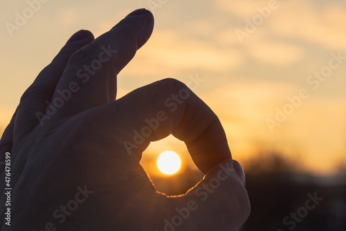 Sign okay (ok) hand (fingers) where the sun is inside. Dawn.