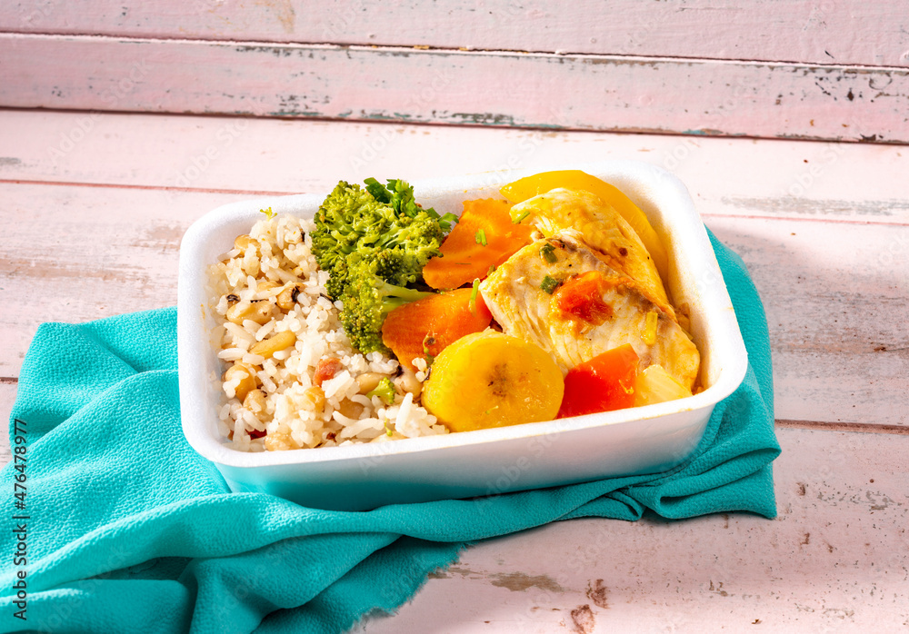 fFish in sauce in lunch box with boiled carrots, brocolis and bananas,  brown rice and white beans, food delivery. Stock Photo | Adobe Stock