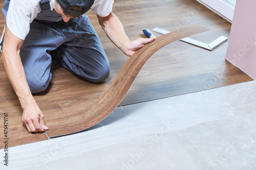 worker joining vinyl floor covering at home renovation photo