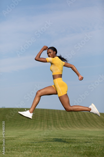 african-American woman in yellow fitness attire during working lunges in the air 0319